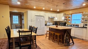 Una cocina con armarios de madera, una isla central y un comedor con sillas.