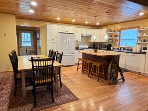 Una cocina con armarios de madera, una isla central y un comedor con sillas.