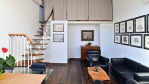 A modern living room with a staircase, a dining table, leather sofas, and framed artwork on the walls. - Charming 38 sqm studio, for 3 people, located on the 2nd floor (attic) of a renovated period building from the 16th century (access only permitted via lift).The property is located in the heart of the historic center of Ravenna (in the restricted traffic (Ravenna)