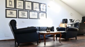 A living room with a black leather sofa, a wooden coffee table, and framed artwork on the wall. - Charming 38 sqm studio, for 3 people, located on the 2nd floor (attic) of a renovated period building from the 16th century (access only permitted via lift).The property is located in the heart of the historic center of Ravenna (in the restricted traffic (Ravenna)