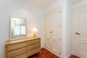 A room with a wooden dresser, a mirror with a bead trim, a lamp, and white double doors. - This one-bedroom apartment at Calle Doctor Fleming 45, just steps from Plaza Castilla, combines contemporary design, comfort, and functionality in a space ideal for extended stays. (MADRID)