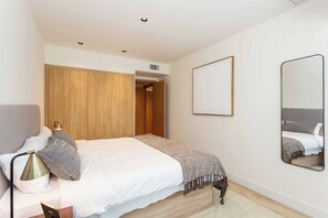 A bedroom with a bed, bedside lamp, and a mirror on the wall. - This apartment with a separate bedroom at Calle Doctor Fleming 45, next to Plaza Castilla, combines elegance, comfort, and functionality in a space ideal for extended stays. (MADRID)