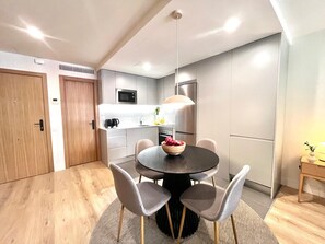 A modern kitchen with a dining area, including a round table with chairs, a microwave, a refrigerator, and a coffee maker. - This contemporary design studio apartment at Calle Doctor Fleming 45, next to Plaza Castilla, offers an elegant, functional, and welcoming accommodation experience, ideal for extended stays. (MADRID)