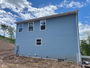 A two-story building with a blue exterior, three windows, and a small attached garage.