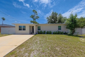 A single-story house with a front yard, a driveway, and a clear sky. - Coastal haven in prime location (Clearwater)