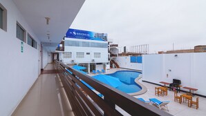 Un área de piscina con sillas de descanso y una parrilla en una terraza.