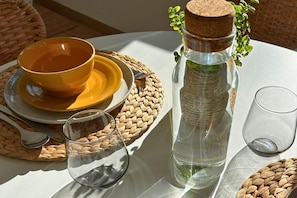 Une table avec une bouteille en verre transparent, un bol jaune et un verre.