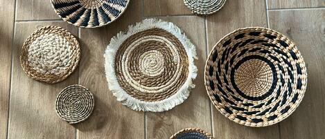 A variety of woven coasters arranged on a wooden floor.