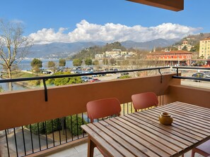 Un balcón con vistas a un lago, montañas y edificios.