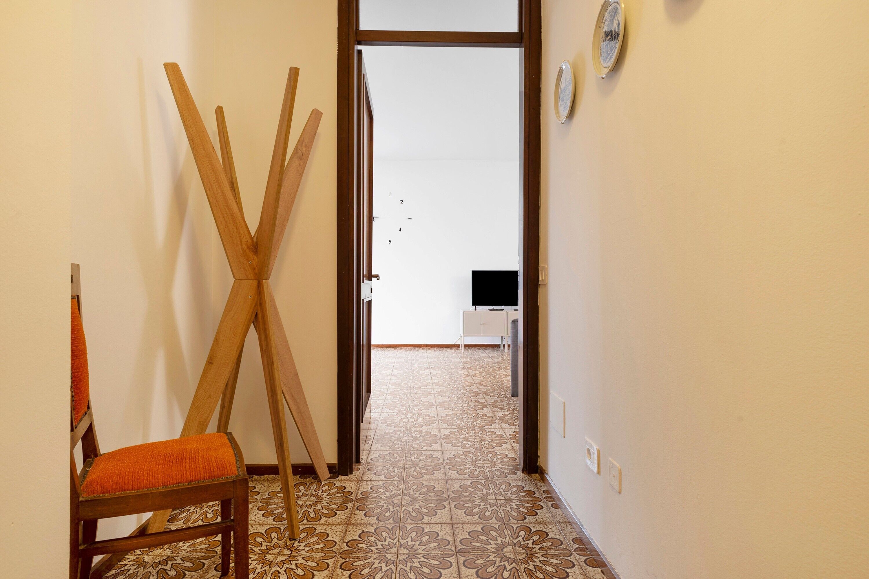 A hallway with a wooden chair, a door, and a patterned floor.