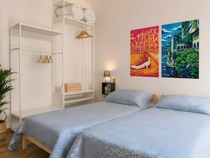 Ein Schlafzimmer mit einem Bett, einem Kleiderschrank, einer Pflanze und zwei Bildern an der Wand.