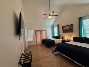 Ein Schlafzimmer mit zwei Betten, einem Deckenventilator, einem Fernseher und einem Bild an der Wand.