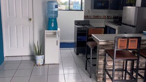 A kitchen with a water dispenser, a clock, a stove, and a refrigerator. - Lodging with the Lopez family in Santa Ana (El salvador)
