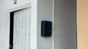 A white door with a number '32' above it, a metal gate, and a wall-mounted device. - Lodging with the Lopez family in Santa Ana (El salvador)