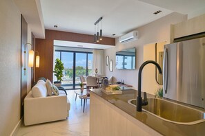 A modern kitchen with a central island, stainless steel appliances, and a dining area with a view. - 2BR Urban Oasis Downtownsd Pool Gym Balcony (Santo Domingo)