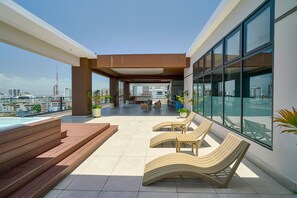 Eine Dachterrasse mit Pool, Sitzgelegenheiten und Blick auf die Stadt.