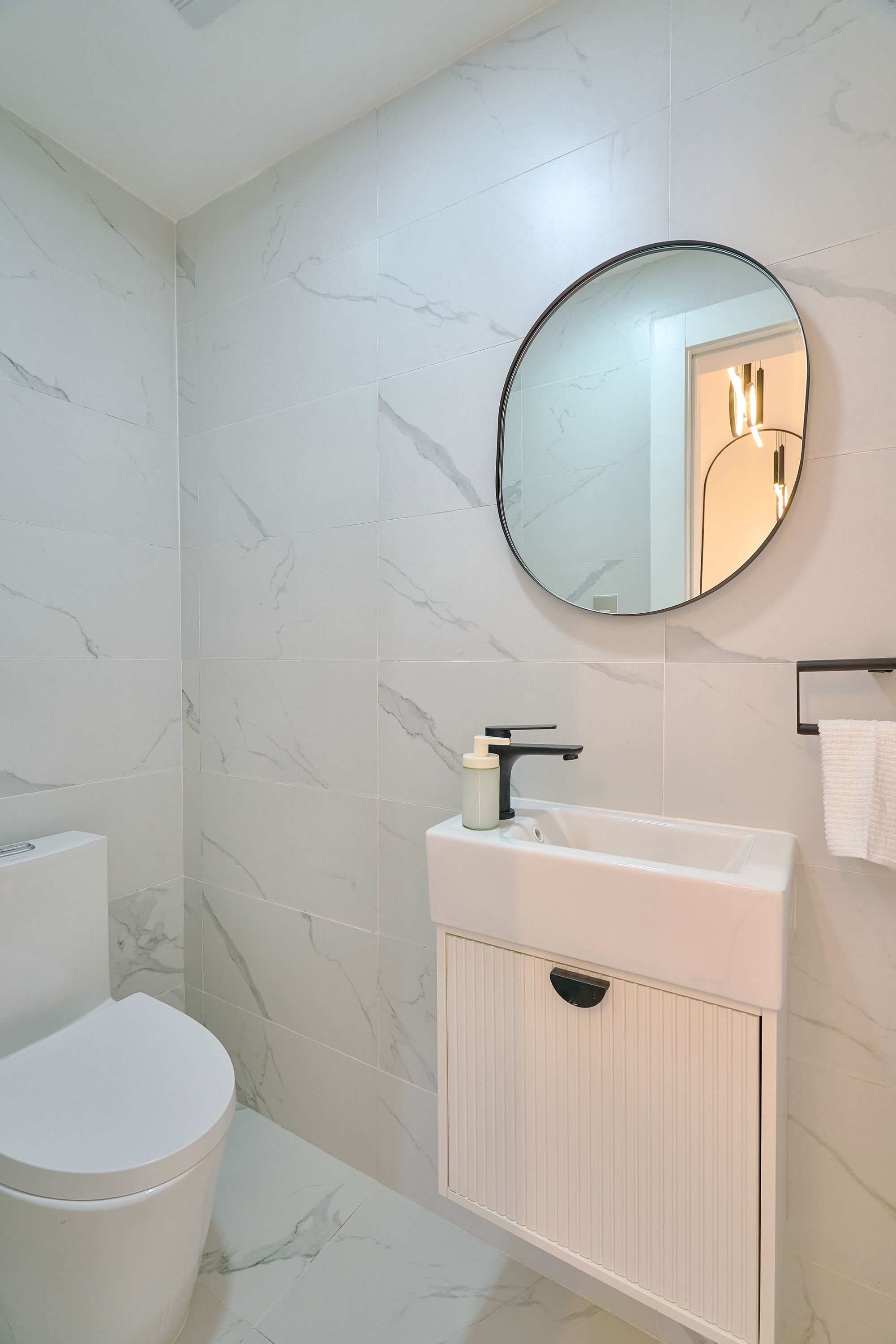 A bathroom with a toilet, a sink with a mirror above it, and a towel rack.