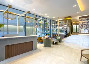 Eine moderne Lobby mit Empfangstresen, Sitzgelegenheiten und einer Marmorwand.