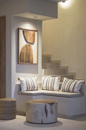 Ein modernes Interieur mit einer eingebauten Sitzbank, einem runden Holzschemel und einem gerahmten Kunstwerk darüber.