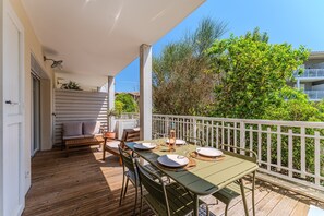 Eine Holzterrasse mit Esstisch, Gartenmöbeln und einem weißen Geländer.