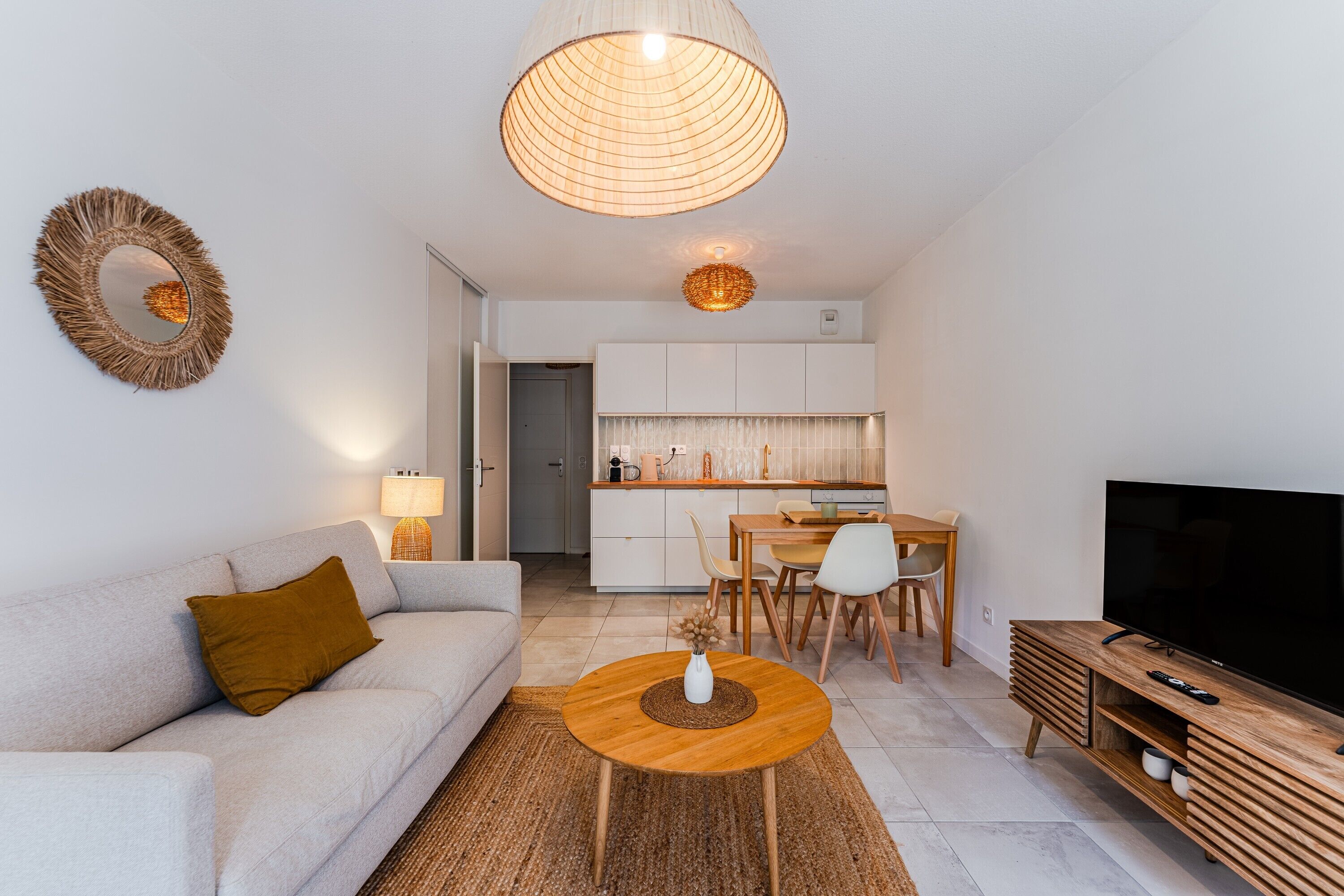 Ein modernes Wohnzimmer mit Sofa, Couchtisch, TV-Schrank und einem Essbereich mit Stühlen und Tisch.