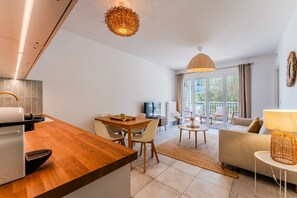 Eine moderne Küche mit Essbereich, einer Couch und einem Fernseher im Hintergrund.