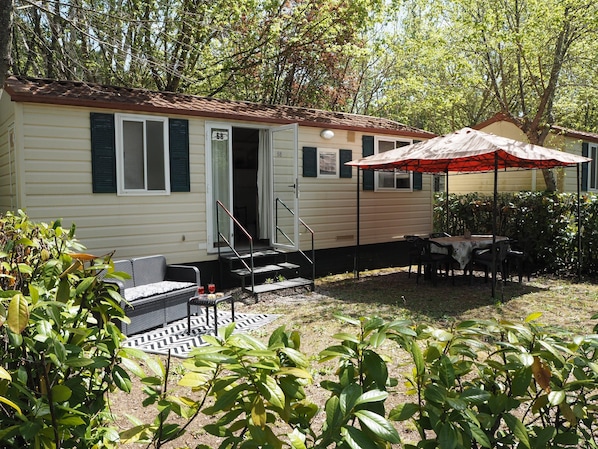 A mobile home with a patio area, outdoor seating, and a covered table. - 2-bed Tuscan Mobile Home With Garden (Bucine)