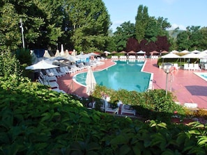 A pool area with lounge chairs and umbrellas, surrounded by greenery. - 2-bed Tuscan Mobile Home With Garden (Bucine)