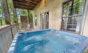 Ein Whirlpool auf einer Holzterrasse mit Blick auf Bäume.