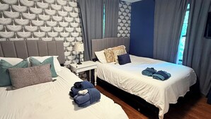 A hotel room with two beds, a nightstand, and a patterned wall. - Stylish house in Raleigh, sleeps 12 (Raleigh)
