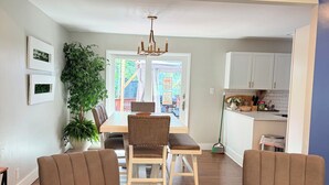 A living room with two brown armchairs, a dining table with chairs, a chandelier, and a view into the kitchen. - Stylish house in Raleigh, sleeps 12 (Raleigh)