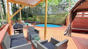 A covered outdoor deck with wicker furniture, a pool, and a grill. - Stylish house in Raleigh, sleeps 12 (Raleigh)
