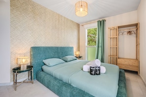 A neatly arranged bedroom with a bed, bedside lamps, a wooden bench, and a window with curtains. - 105 L l Gant in Cannes (Cannes)