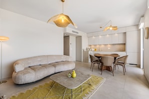 A modern living room with a sofa, a coffee table, and a dining area with chairs. - 105 L l Gant in Cannes (Cannes)