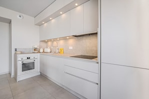 A modern kitchen with white cabinetry, a built-in oven, a sink, and under-cabinet lighting. - 105 L l Gant in Cannes (Cannes)