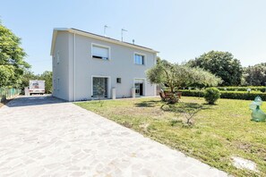 A two-story building with a paved driveway, a small garden with a tree and a bench, and a clear sky. - Wonderful private villa for 6 people with A/C, WIFI and veranda (Fano)