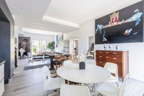 A modern dining area with a round table, white chairs, and a large painting on the wall. - Wonderful private villa for 6 people with A/C, WIFI and veranda (Fano)