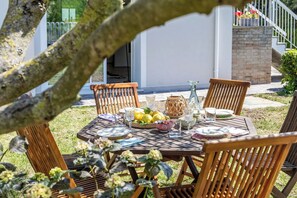 An outdoor dining area with a wooden table set for four, surrounded by wicker chairs. - Wonderful private villa for 6 people with A/C, WIFI and veranda (Fano)