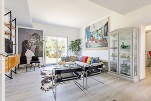A modern living room with a sofa, a glass coffee table, a large painting, and a cabinet with glass doors. - Stunning private villa for 6 people with WIFI, A/C and veranda (Fano)