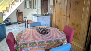 Un coin repas avec une table dressée pour deux personnes, un buffet en bois et un escalier en arrière-plan.