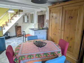 Ein Essbereich mit einem Tisch für zwei Personen, einem Holzkabinett und einer Treppe im Hintergrund.