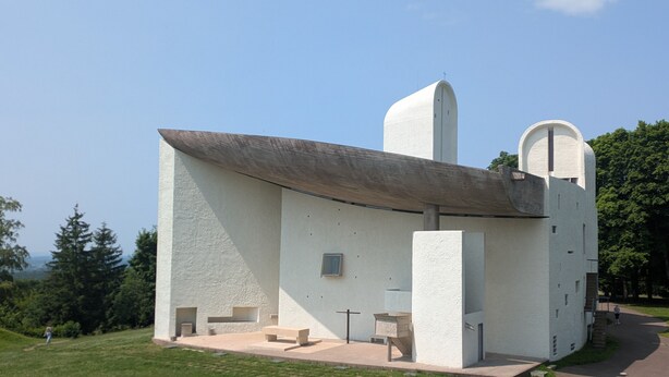 Un bâtiment moderne doté d’un toit incurvé, d’une tour centrale et d’une petite fenêtre.