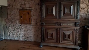 Une pièce avec un mur en pierre, une armoire en bois et un plancher en bois.