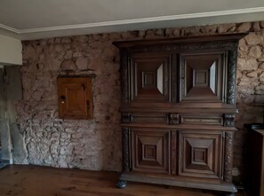 Ein Zimmer mit Steinwand, Holzschrank und Holzboden.