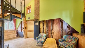 Ein Zimmer mit einer Holztreppe, einem Holztisch und zwei gemusterten Stühlen.