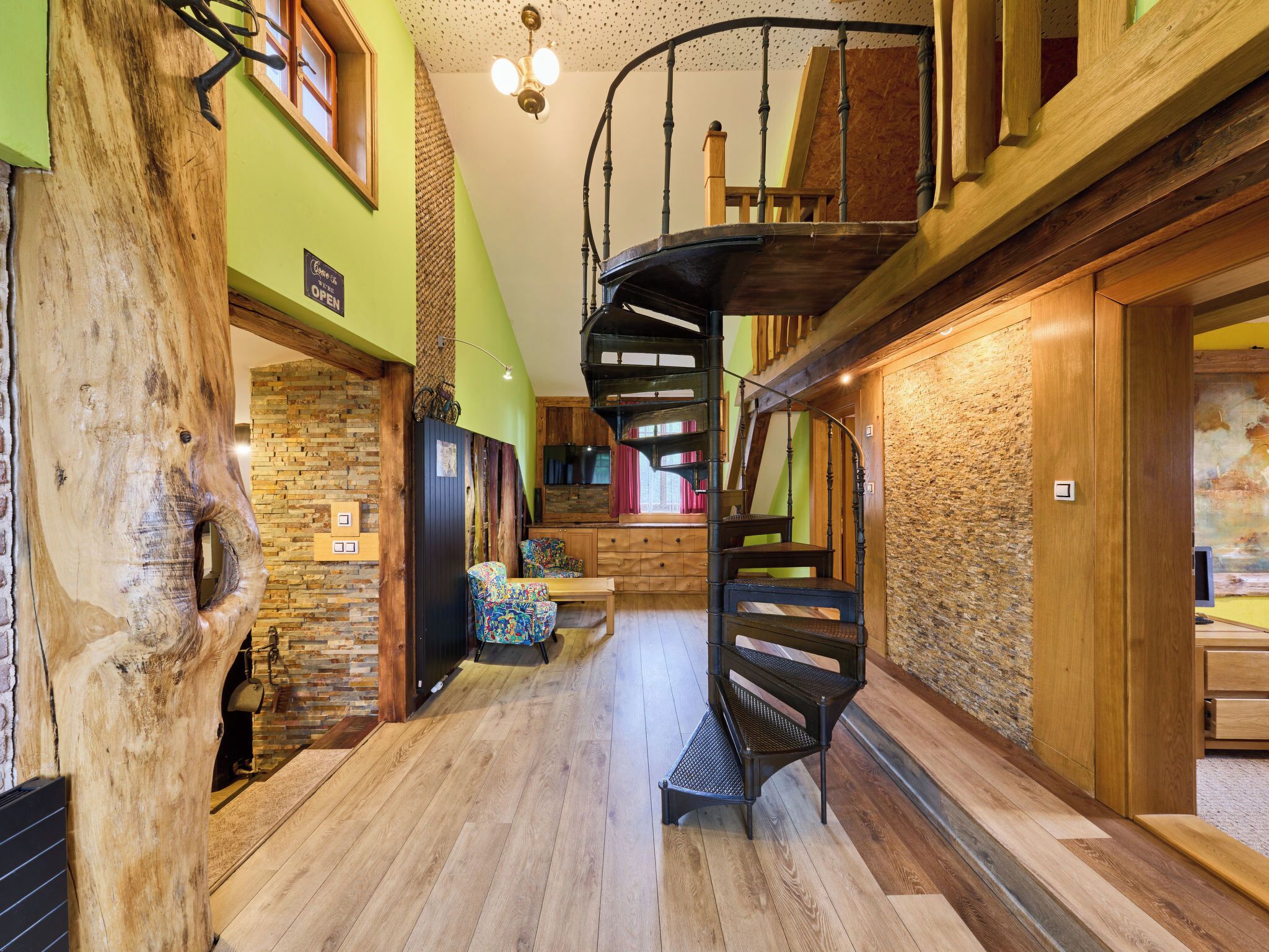 Eine Wendeltreppe in einem Holzinnenraum mit einer Steinwand und einem großen Baumstamm.