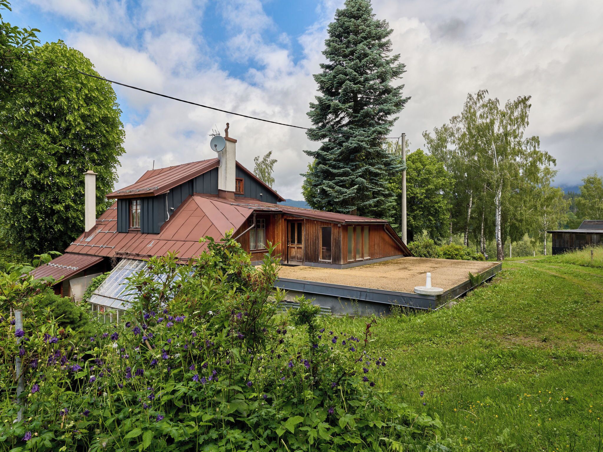 Ein Haus mit geneigtem Dach, Schornstein und einer kleinen Terrassenfläche.