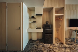 A compact hotel room with a kitchenette, a small sink, a microwave, and a television. - Moat Inside Hakata (Fukuokasi Hakataku)