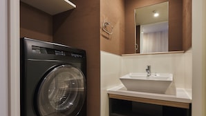 Un baño pequeño con lavadora integrada y lavamanos pedestal.