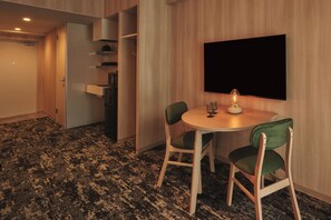 A room with a round table, two chairs, a flat-screen TV mounted on the wall, and a carpeted floor. - Moat Inside Hakata (Fukuokasi Hakataku)